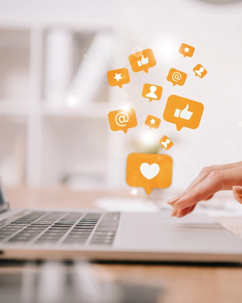 Mão a usar computador com ícones de redes sociais para gestão digital
